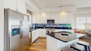 A modern kitchen with white cabinets, stainless steel appliances, and a central island with stools.