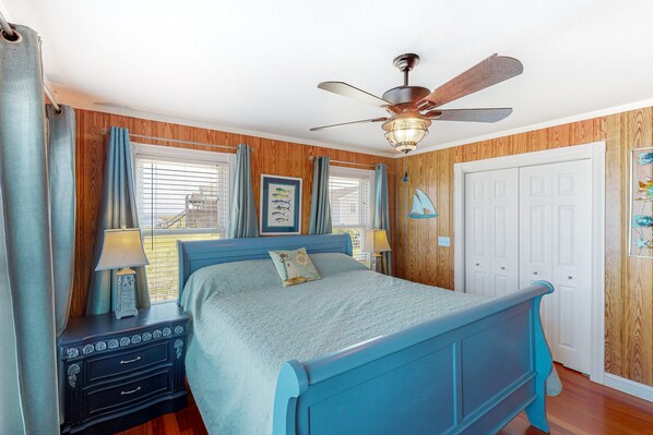 A bedroom with a bed, nightstands, a ceiling fan, and wooden walls. - Reel Living #3-AV: Dog-Friendly, Waterfront Home, Hot Tub (Avon)