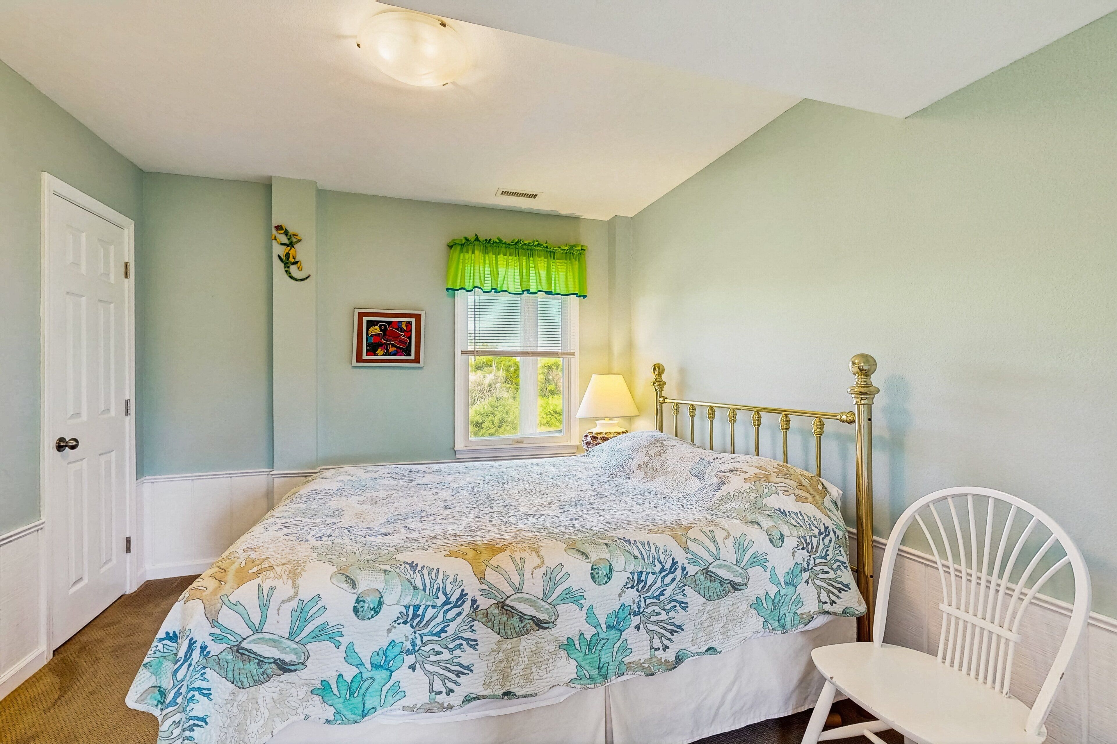Une chambre à coucher comprenant un lit, une chaise, une fenêtre avec des stores, une porte et un tableau accroché au mur.