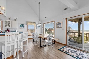 A dining area with a table and chairs, a kitchen area with cabinets, and a large sliding glass door to a deck.