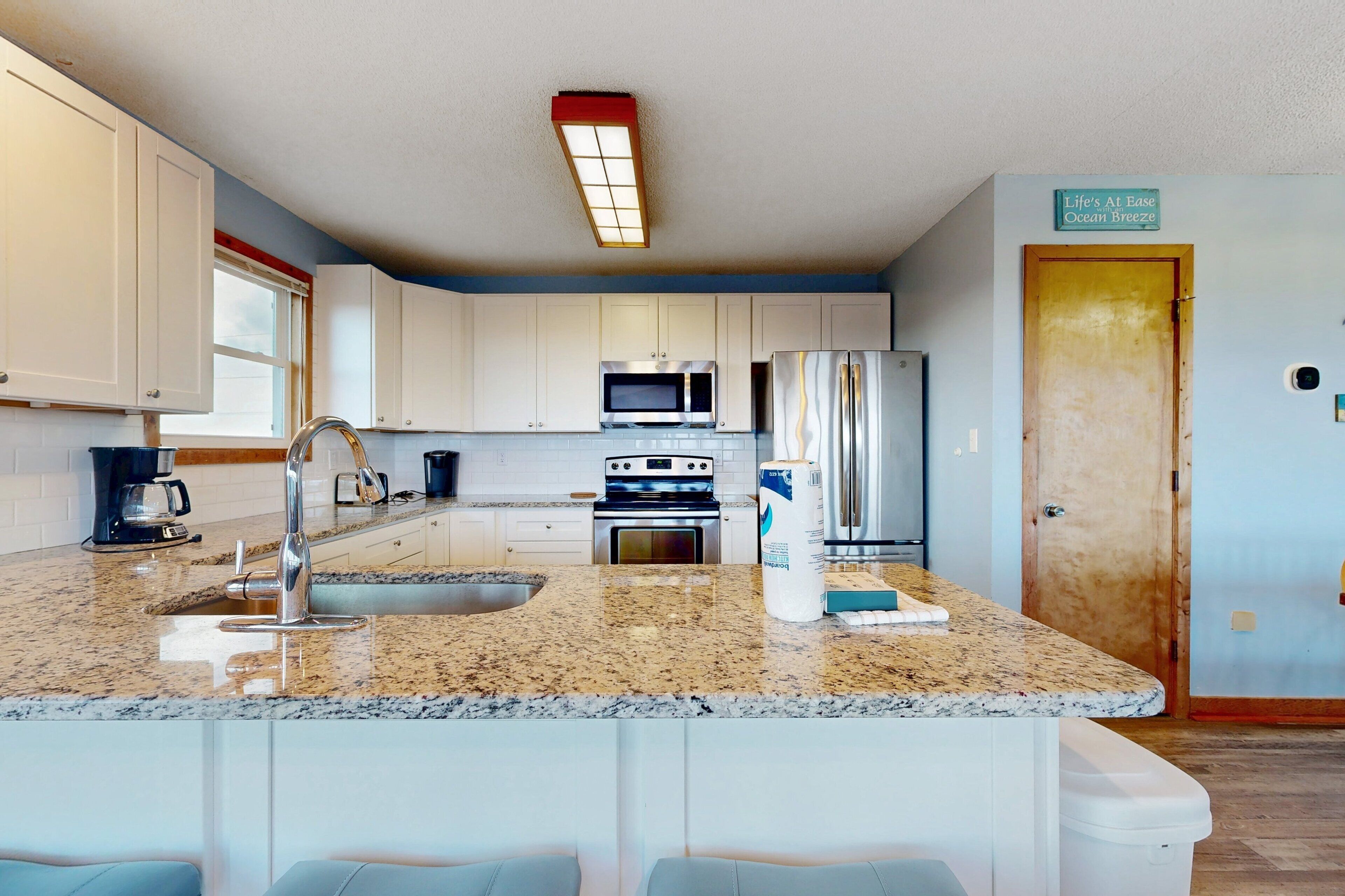 A modern kitchen with granite countertops, stainless steel appliances, and white cabinetry.