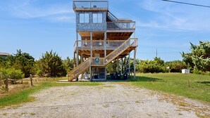 A multi-level wooden structure with a staircase, surrounded by greenery. - Attitude Adjustment: Dog-friendly, ocean/sound views, shared pool (Avon)