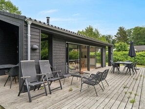 A covered outdoor patio with a wooden deck, metal chairs, and a table.