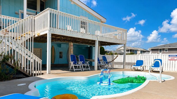 Ein Poolbereich mit kleinem Pool, Liegestühlen und einer überdachten Terrasse.
