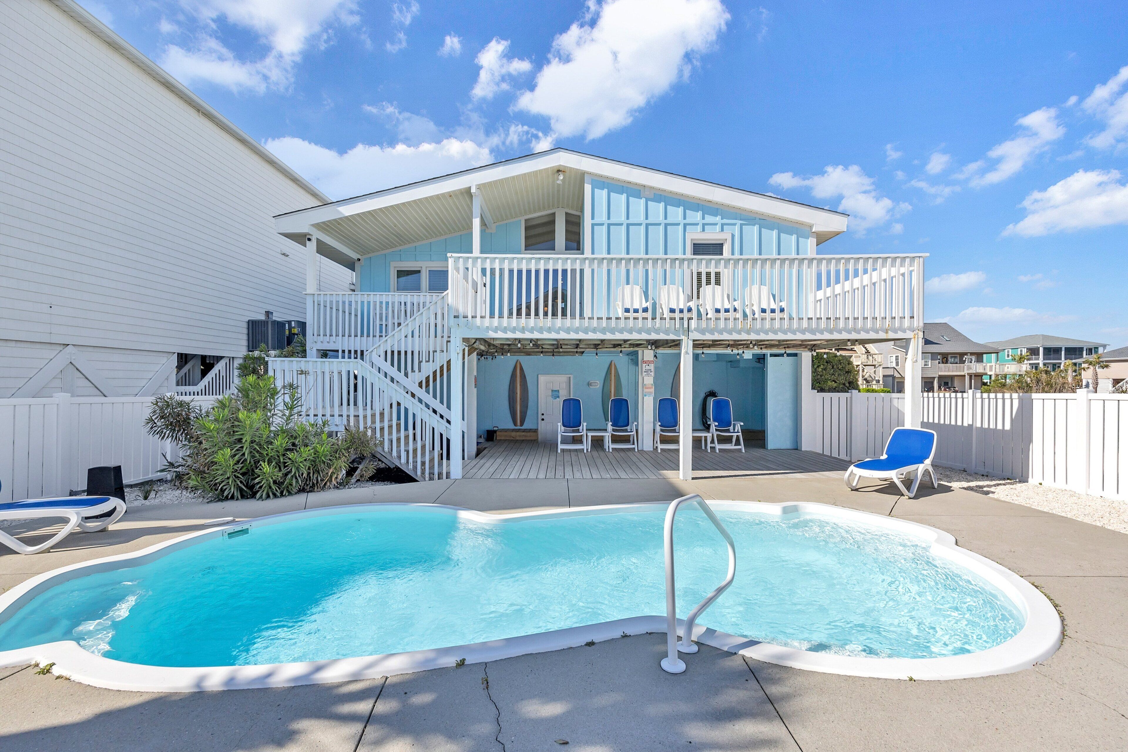 A two-story house with a swimming pool, a covered deck, and a fenced backyard.
