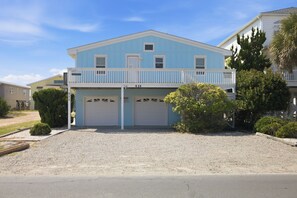 Une maison à deux étages, avec une façade bleue, un porche à l’avant et deux portes de garage.