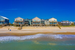 A beachfront property with multiple buildings, wooden walkways, and a sandy beach. - Conveniently located ocean & beachfront home with beach access & outdoor shower (North Topsail Beach)
