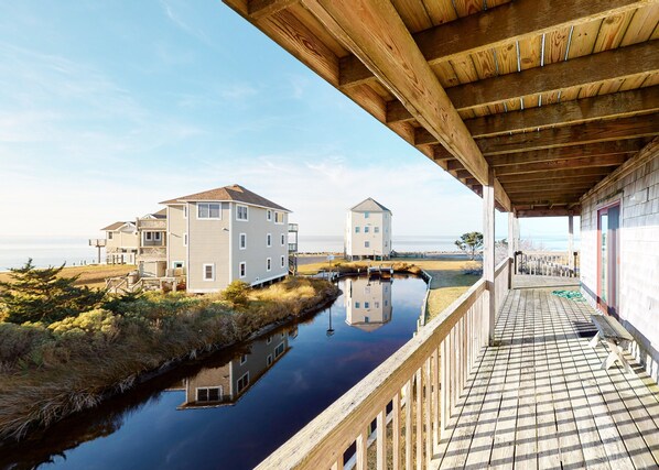 A waterfront property with a wooden deck, a canal, and two buildings with a white facade. - Waterfront House w/ Sound View, Free WiFi, Private Washer/Dryer, Shared Pool (Frisco)