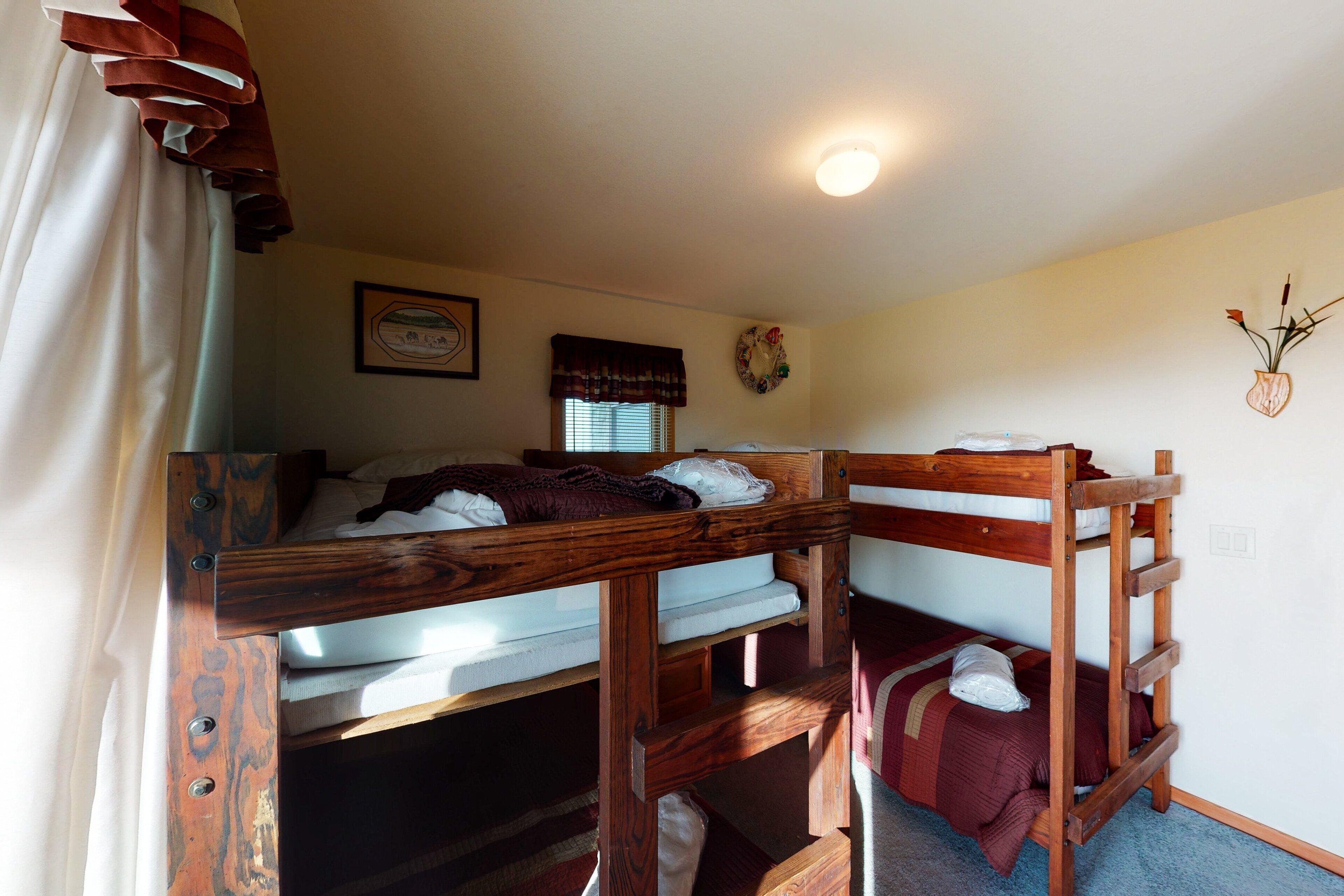 A bunk bed room with a window, a framed picture, and a wall-mounted decoration.