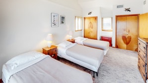 Habitación de hotel con dos camas, un aparador de madera, una mesita de noche roja y un estante con adornos.