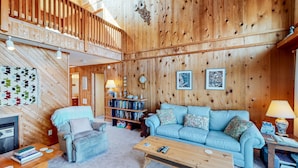 Un salón acogedor con detalles de madera, un sofá azul, una mesa de centro de madera y una estantería llena de libros.