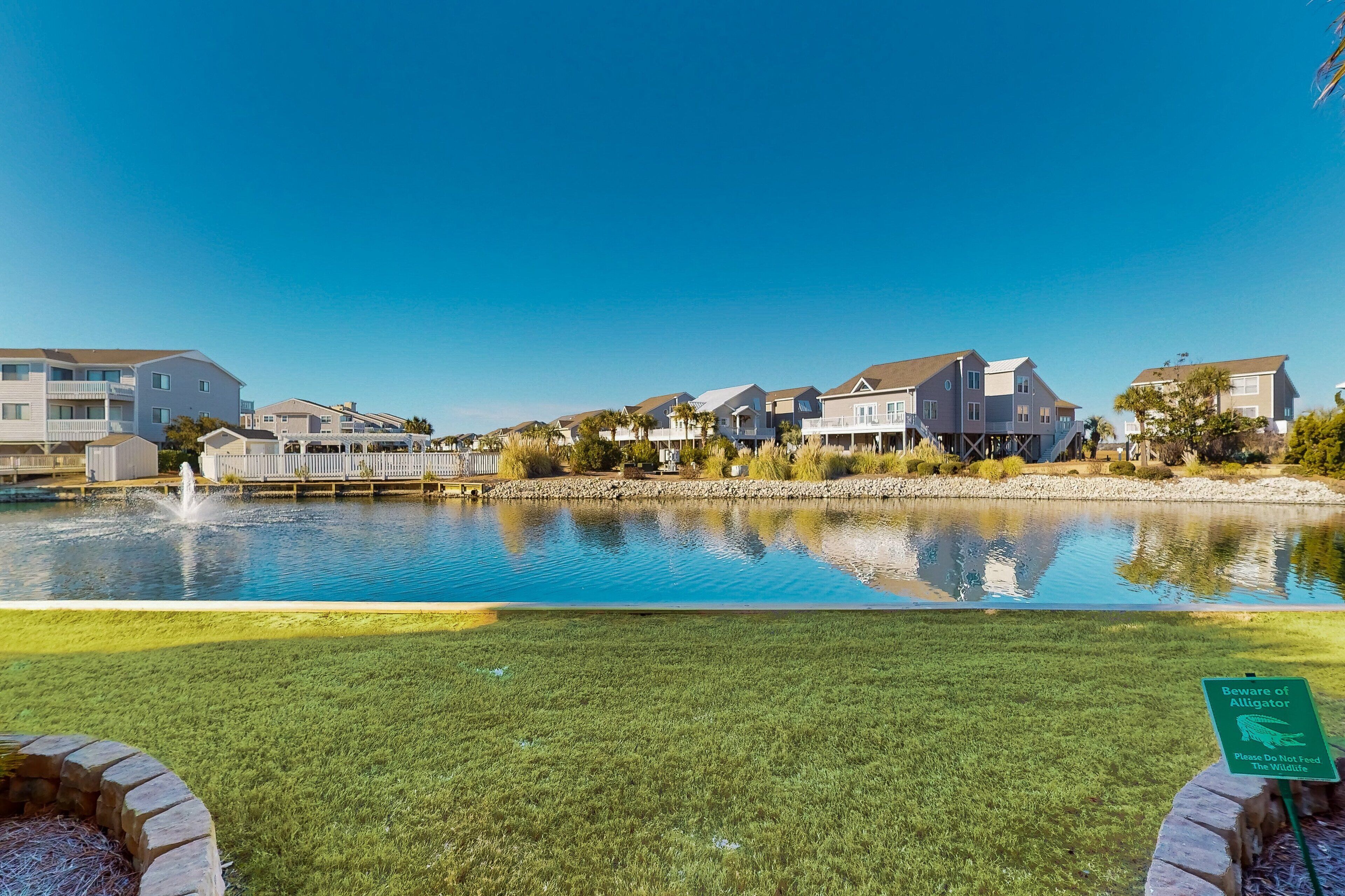 A residential area with a swimming pool, houses, and a warning sign about alligators.