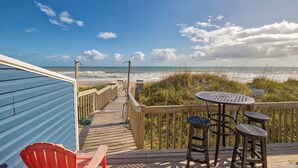 A wooden deck with a view of the ocean, a table with chairs, and a red chair. - Ocean-view townhome - beach access, central AC, W/D, ocean views - dog-friendly (North Topsail Beach)