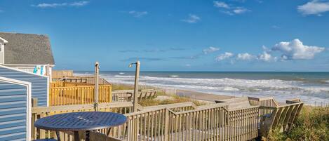 A wooden deck with a table and chairs overlooking the beach.