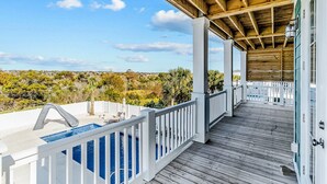 Une terrasse en bois avec une piscine, des rampes blanches et une vue sur le paysage.
