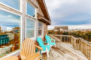 A wooden deck with two chairs and a table, overlooking a cityscape.