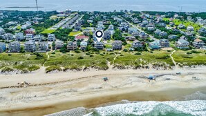 An aerial view of a coastal residential area with houses, a beach, and a marked location. - Oceanfront house w/private hot tub, balcony, washer/dryer, WiFi, central AC (Waves)