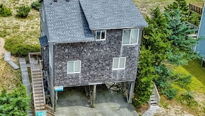 A two-story house with a sloped roof, a front porch, and a visible garage. - Oceanfront house w/private hot tub, balcony, washer/dryer, WiFi, central AC (Waves)