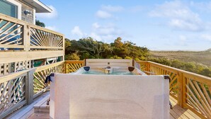 A wooden deck with a hot tub, overlooking a scenic landscape.