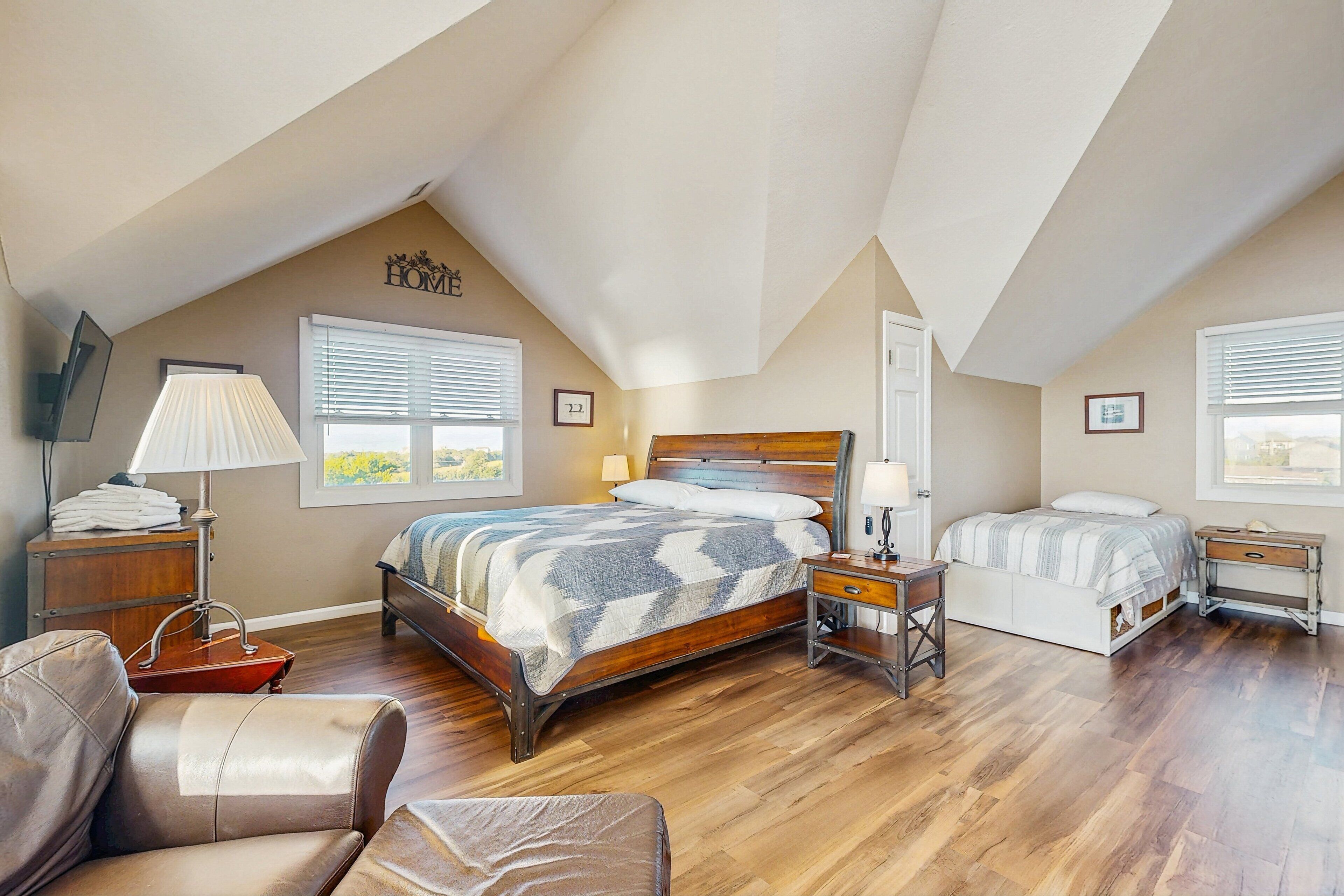 A bedroom with a large bed, two bedside tables, a chair, and a desk.