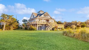 A large two-story house with a spacious front yard, a covered porch, and a staircase leading to the main entrance.