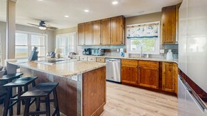 A kitchen with wooden cabinets, a granite countertop, a dishwasher, and a refrigerator.