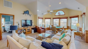 A spacious living room with a large sofa, a television, and a ceiling fan.