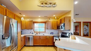 A modern kitchen with wooden cabinets, stainless steel appliances, and a large island.