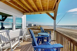 A wooden deck with Adirondack chairs and a table, overlooking a beach. - Summer Sands: Waterfront, Dog Friendly, Balcony (Ocean Isle Beach)