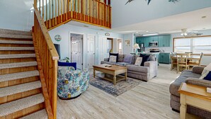 A spacious living area with a wooden staircase, a kitchen, and a dining area. - Summer Sands: Waterfront, Dog Friendly, Balcony (Ocean Isle Beach)