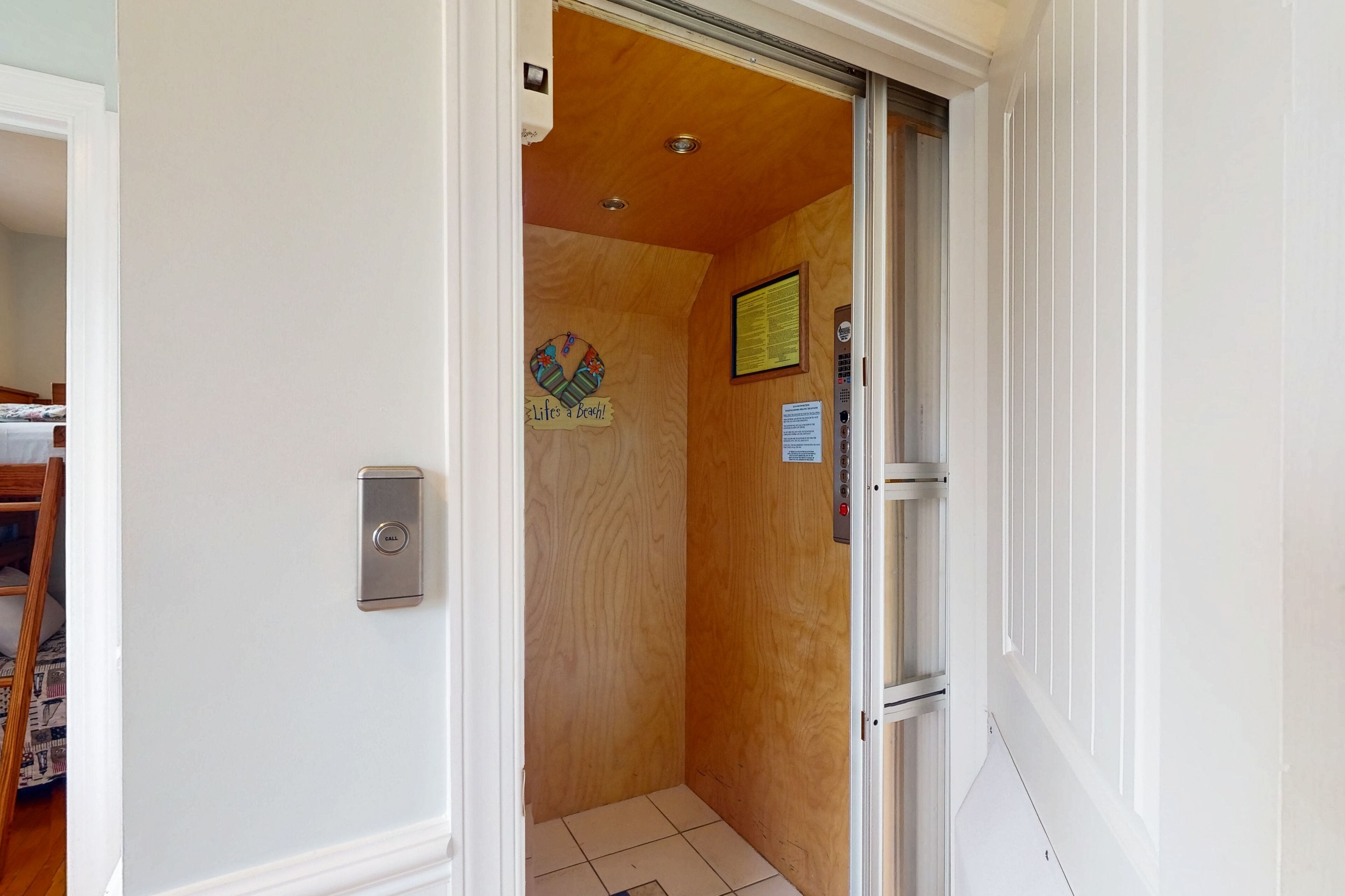 A narrow hallway with a wooden door leading to a room.