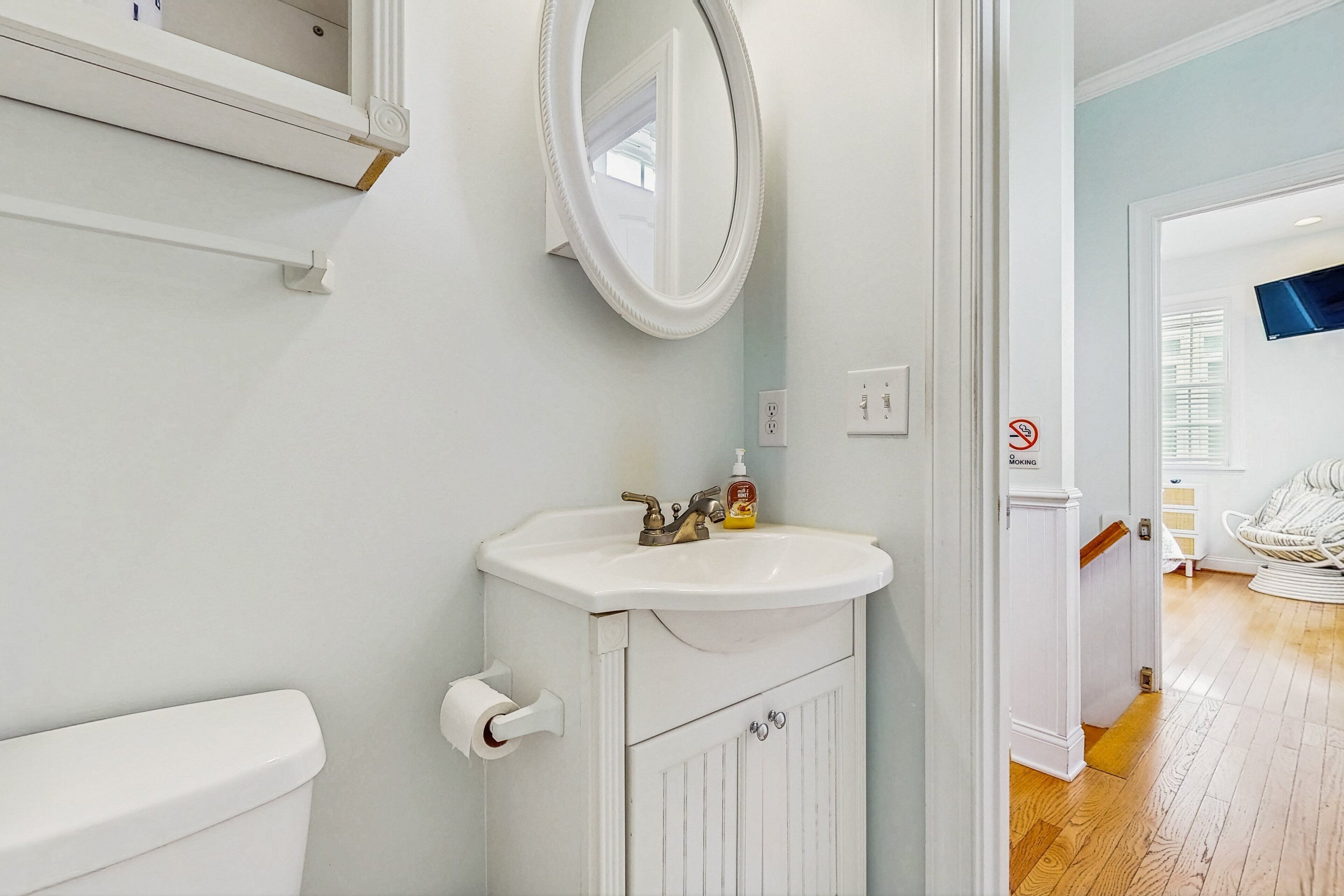 A bathroom with a white sink, a toilet, and a mirror.