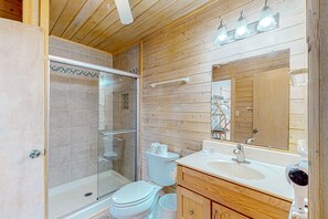 Un bagno con doccia vetrata, un water e un mobile lavabo con specchio.