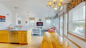 Une cuisine spacieuse dotée de meubles en bois, d’un îlot central et d’un coin repas avec une longue table en bois.