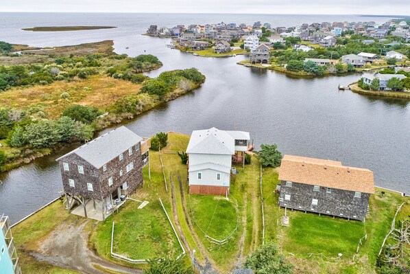 Una vista aerea di una zona residenziale con case lungo un corso d'acqua, caratterizzata da un mix di edifici unifamiliari e a più piani, alcuni con garage integrati.