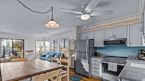 Eine moderne Küche mit Edelstahlgeräten, ein Essbereich mit Holzmöbeln und einem Deckenventilator.