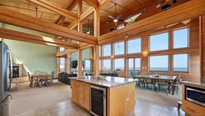 A spacious kitchen with a large island, wooden beams, and large windows.