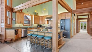 A spacious kitchen with wooden cabinets, a central island with stools, and a view of the outdoors.