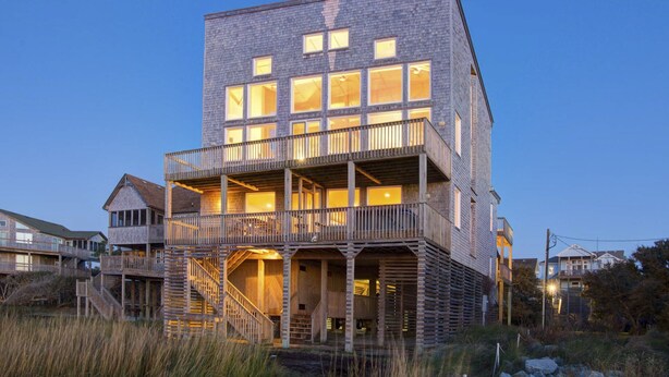 A multi-story building with a wooden deck and a staircase leading to the upper levels.