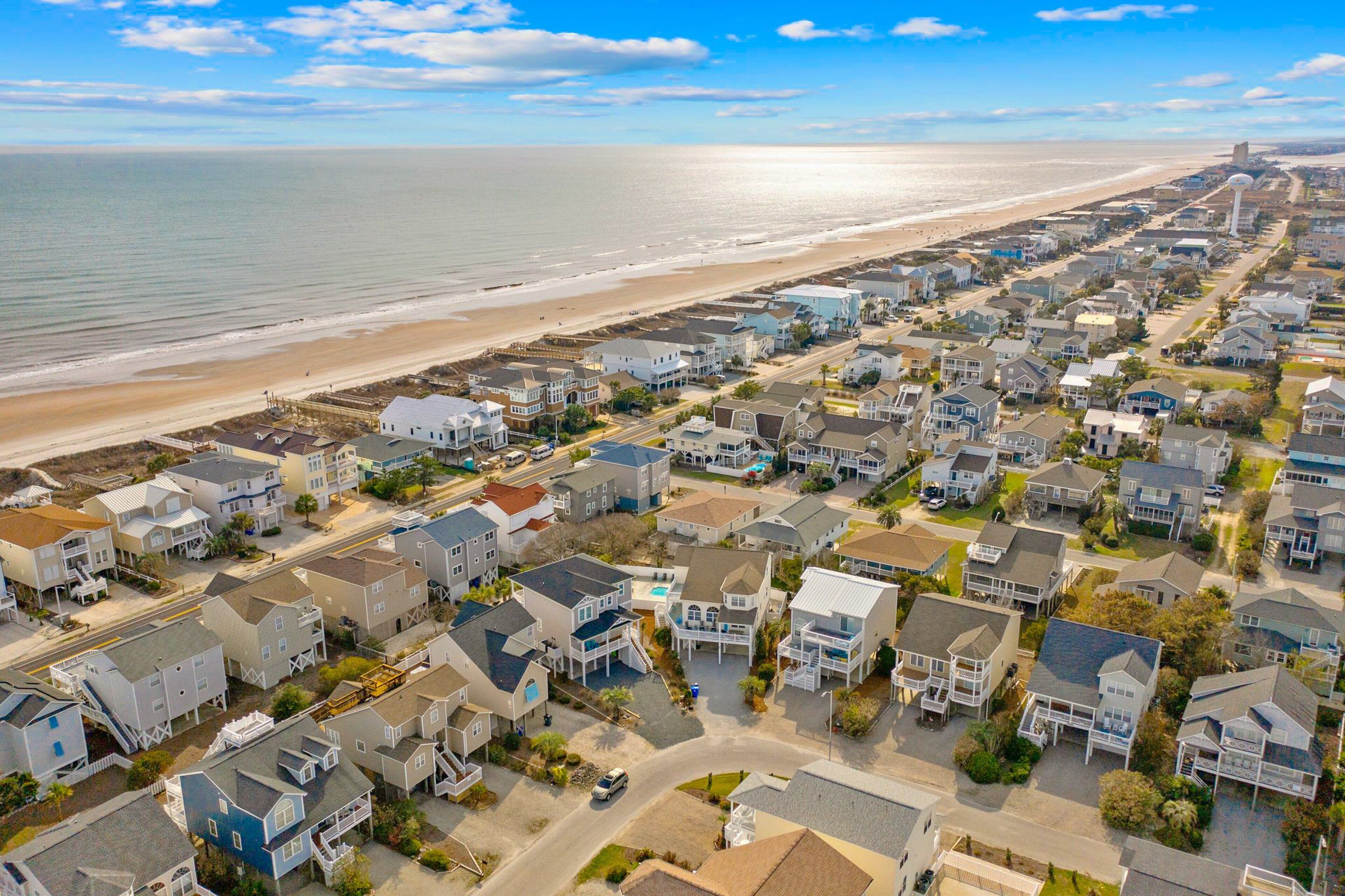 A coastal residential area with houses, a beach, and a clear sky.