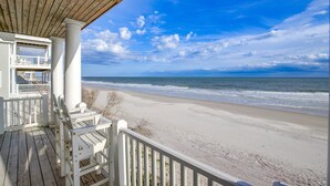 Une terrasse en bois avec des rampes blanches donnant sur une plage.