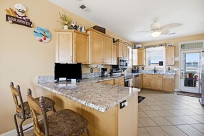 A kitchen with granite countertops, wooden cabinets, a built-in oven, and a ceiling fan.