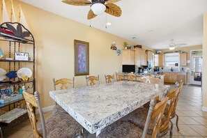 A spacious kitchen with a large island, wooden chairs, and a ceiling fan.