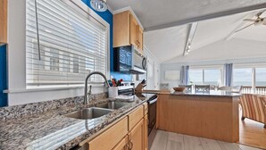 Uma cozinha moderna com bancadas de granito, micro-ondas embutido e armários de madeira.
