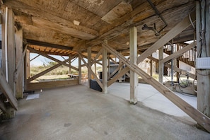 An open wooden structure with a concrete floor, visible beams, and a view of the outdoors.