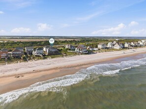 Une zone résidentielle côtière avec des propriétés donnant sur la plage, un ciel dégagé et un panneau indiquant « Côte de Caroline ».