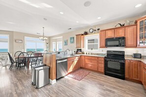 A spacious kitchen with wooden cabinets, a stainless steel refrigerator, a microwave, and a stove.