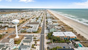 A coastal residential area with a long road leading to the beach, houses with balconies, and a water tower.