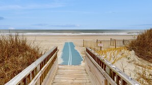 A wooden boardwalk leading to a beach with a sign indicating 'Dune'.