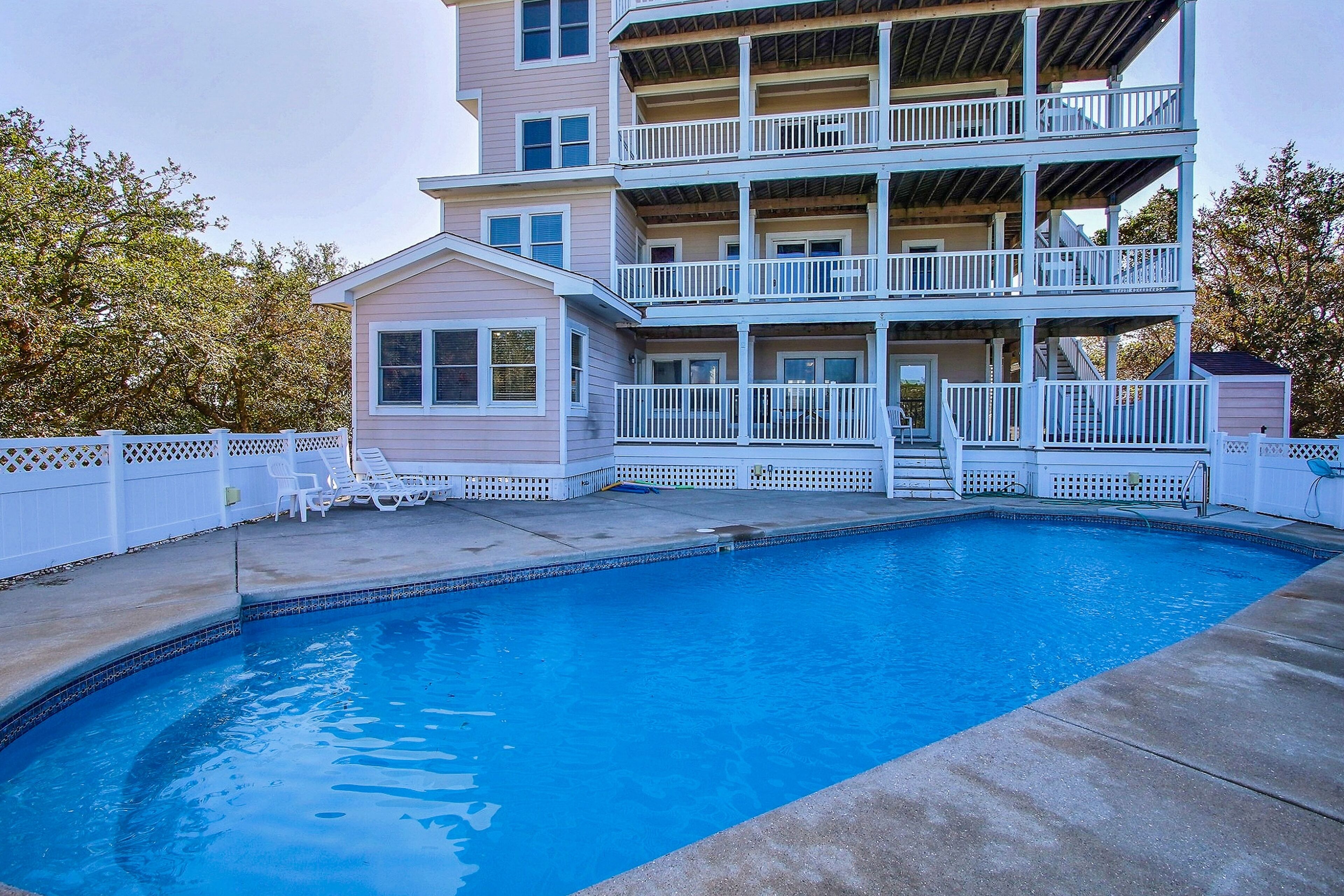 A two-story building with a swimming pool, white railings, and a covered patio area.